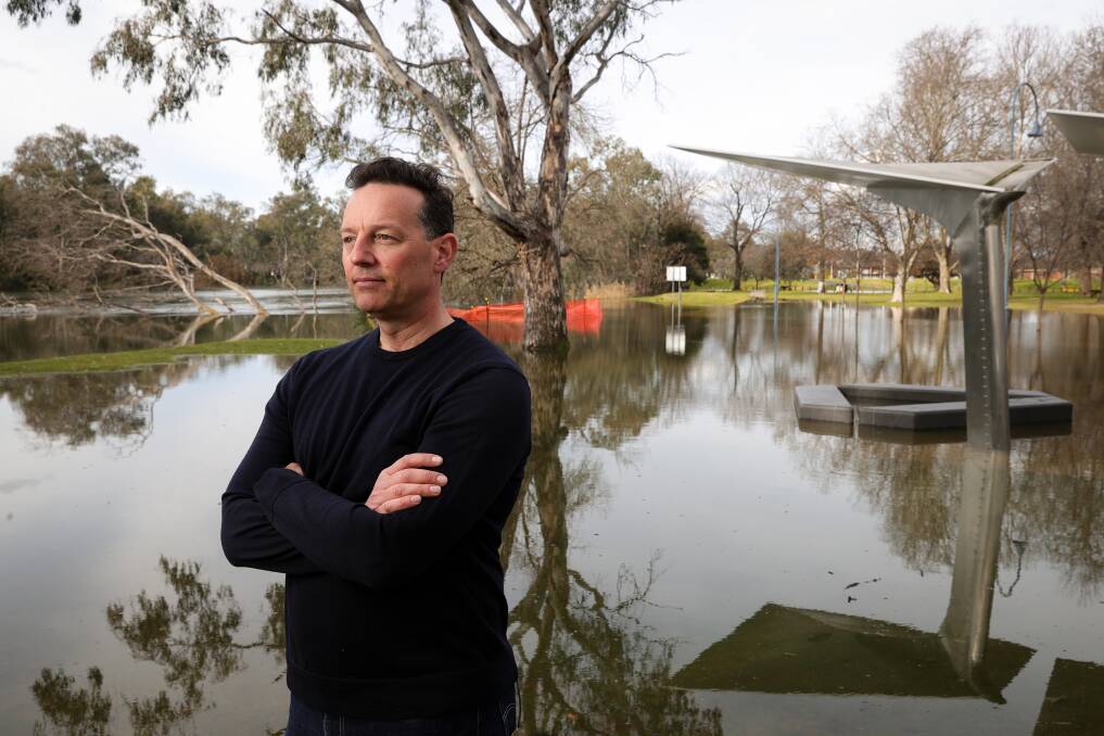 River Deck Cafe operator Alex Smit stands before flooded Noreuil Park as waters keep rising forcing the eatery to close. Picture: JAMES WILTSHIRE