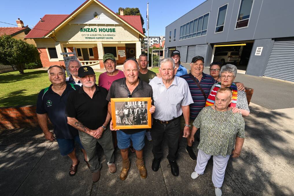 Veteran Colin Darts holds a picture showing vets holding up the banner in 1986, with Bill Godde (right), Gayle McDonald who made the banner 48 years ago (far right) and a group of supporters. Picture by Mark Jesser 