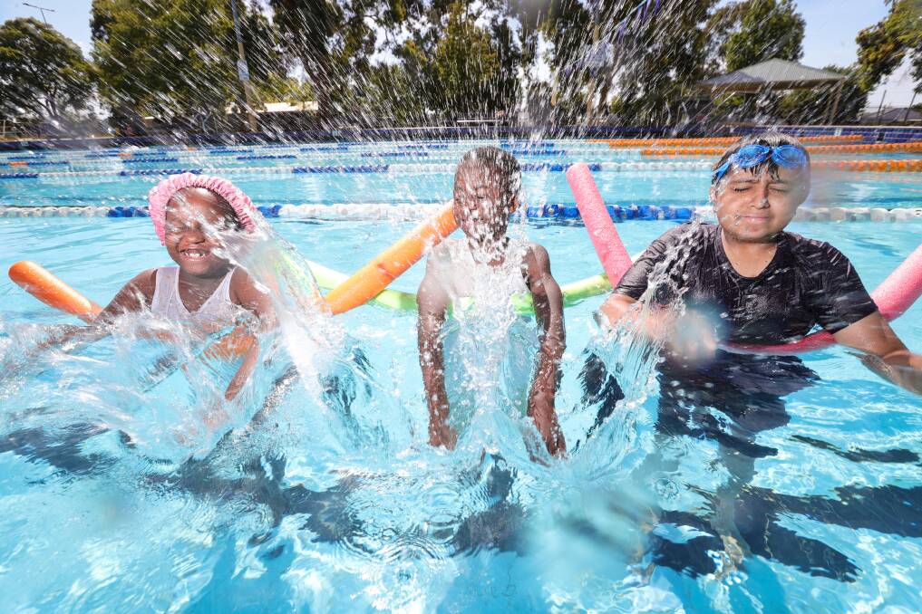 Donel, 8, Jaasciel Kafwa, 9, and Samir Koirala, 11, make a splash at the first day of a week-long intensive learn to swim program at Lavington Swim Centre. Picture by James Wiltshire.