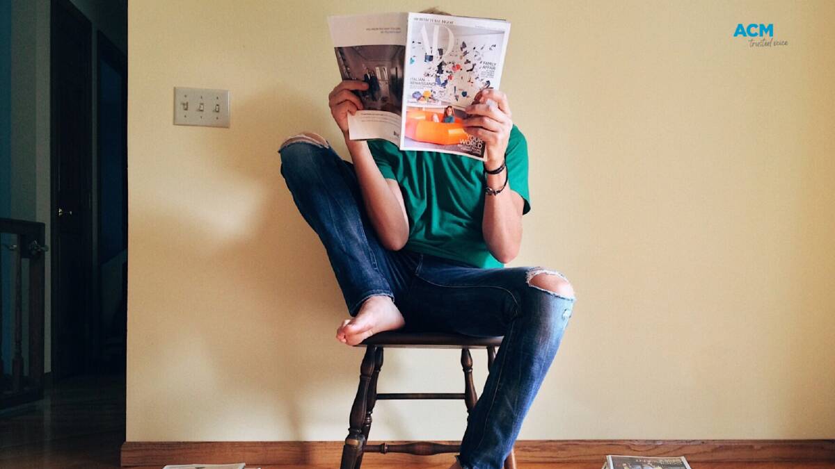 Person sits on a stool reading a magazine. File picture.