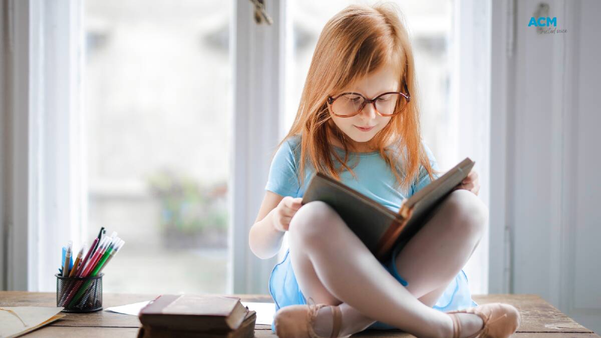 A child sits cross-legged reading a book. File picture.