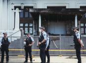Police guard the front of Old Parliament House the day after violent protesters lit a fire which severely damaged the building's front portico. Picture: Dion Georgopoulos
