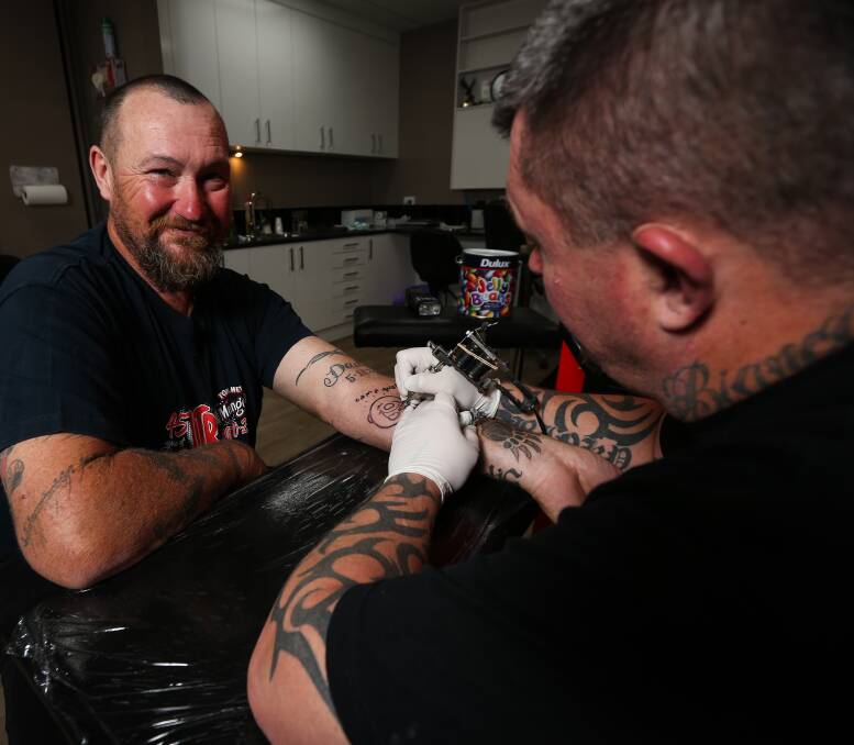 FRESH INK: Twin City Tattoo and Body Piercing's tattoo artist Cheyne O'Brien works on Wodonga man Craig Nolan's Camp Quality logo Giggles on Monday. The appeal has raised $1400 so far. Picture: JAMES WILTSHIRE