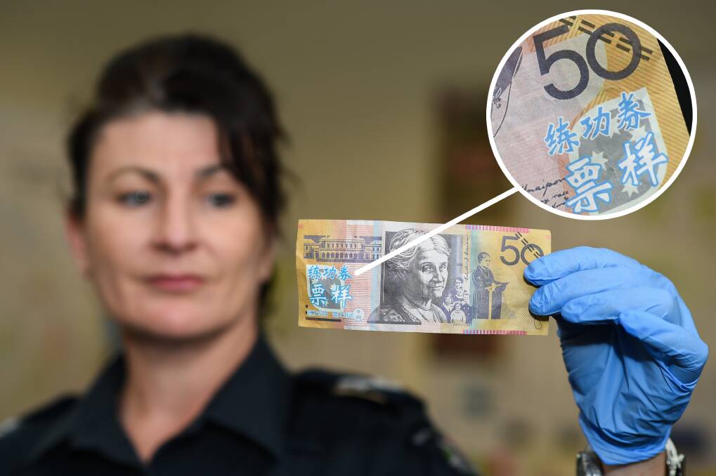 COUNTERFEIT CASH: Senior Constable Donna Allen with the fake note showing blue foreign writing, pictured on both sides. Picture: MARK JESSER