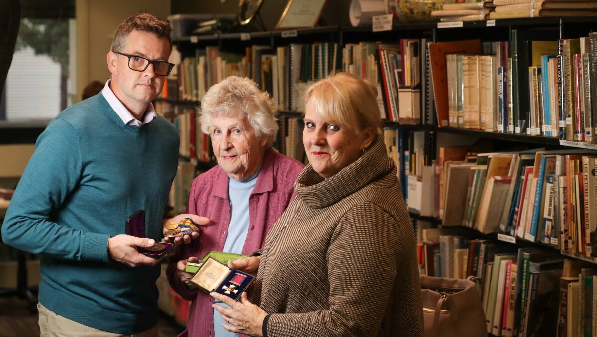 SERVICE: Wodonga Family History Society's librarian Lyn Larkin and program coordinator Janette Griggs look at military medals from World War One with Border Mail journalist John Chanter.