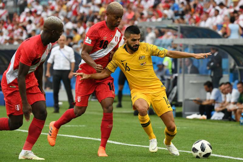 Australia's Aziz Behich is tackled by Andre Carrillo of Peru. Photo: AAP