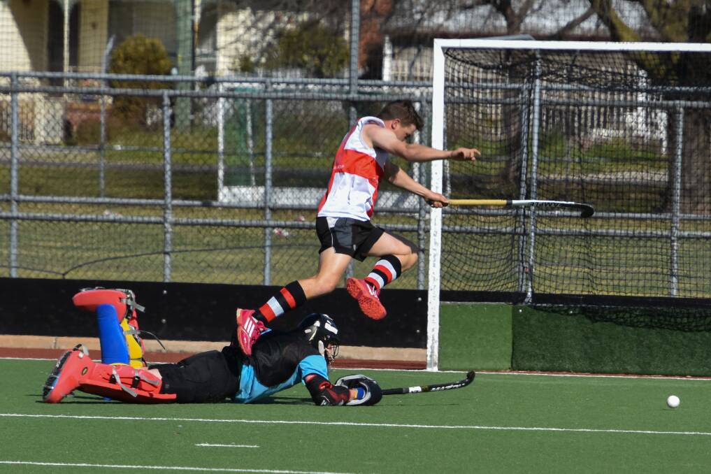 DETERMINED: Red's Aidan McMillan leaps over the top of Black's Patrick Baine in an attempt to score for his side during Hockey Albury-Wodonga's eight's competition on the weekend. Picture: GORDON ARNOLD