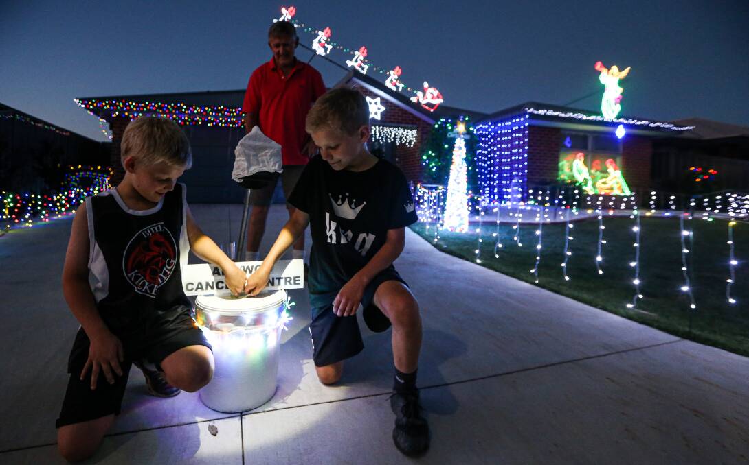 GENEROSITY: Kevin Allitt looks on from his Thurgoona home as Alex, 9 and John Brown, 11, make a donation to the Albury Wodonga Regional Cancer Centre after enjoying the Christmas display. Picture: JAMES WILTSHIRE