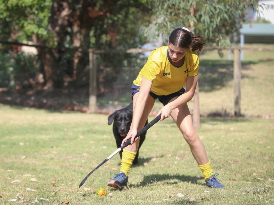 TRAINING PARTNER: Summer practices her hockey skills in her backyard in Kiewa with some assistance from her dog Remi.