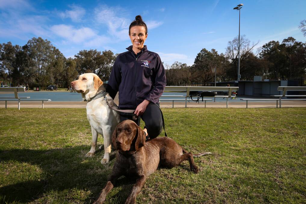 LOYAL COMPANIONS: Thurgoona netballer Mardi Nicholson with her dogs Gary and Donnie at the home of the Bulldogs. Nicholson helped Thurgoona to a fifth place finish in A-grade this season. Picture: JAMES WILTSHIRE