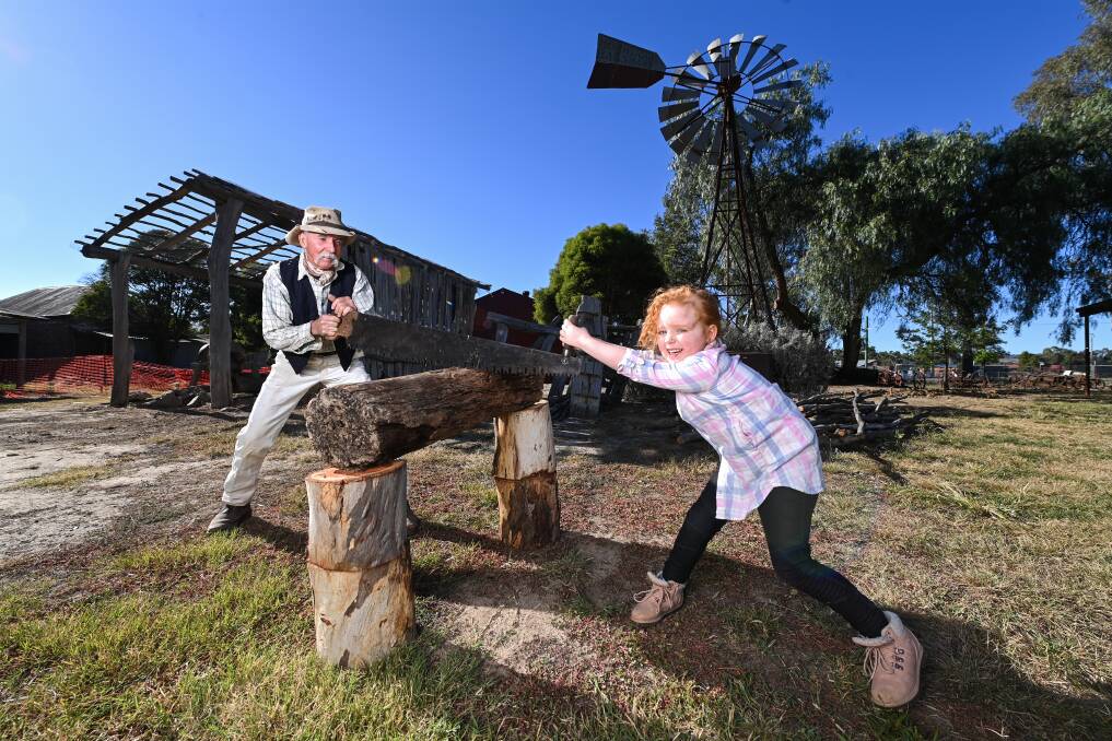 LOST TRADES: MacIan 'Sapper' Sutherland shows Amelia Clarke, 5, how people once used to cut timber before machines did the hard work. He will be demonstrating his skills at the Jindera Pioneer Museum open day on March 21. Picture: MARK JESSER