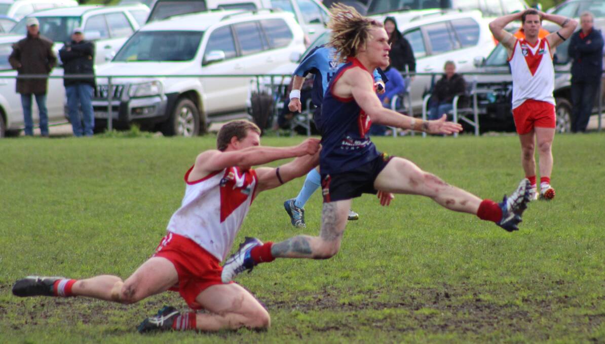 ON THE FRONT FOOT: Corryong's David Low gets a kick away despite pressure from Swan Nick Bond on Saturday. Pictures: CORRYONG COURIER