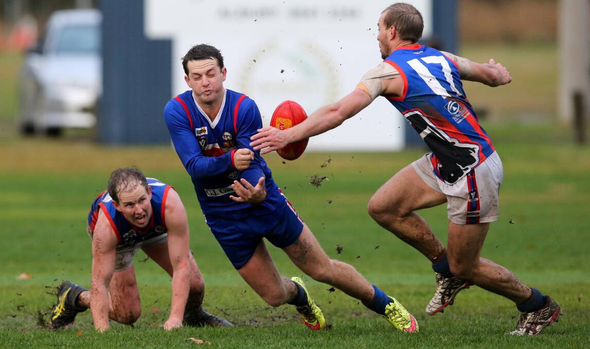  Thurgoona's Dylan Rake dishes off a handball for the Bulldogs while under pressure from Beechworth's Kayde Surrey.