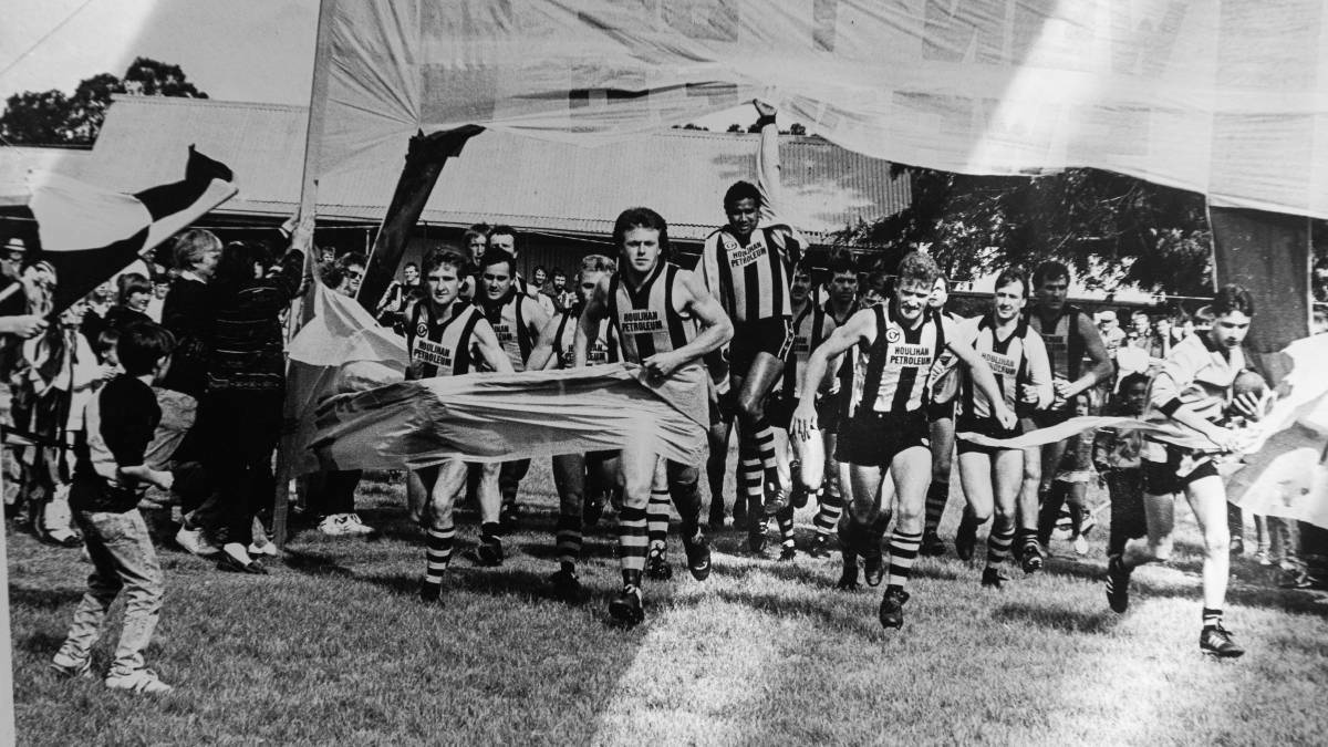 Wayne Edwards (centre) springs into the air as Walbundrie's players break through the banner before the 1989 grand final against East Lavington.