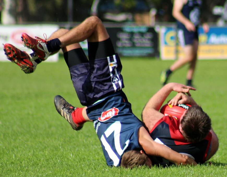 Cudgewa's Sam Stephens bends over backwards to tackle Corryong president Owen Johnstone at Corryong on Saturday. Picture: DEB HARRAP