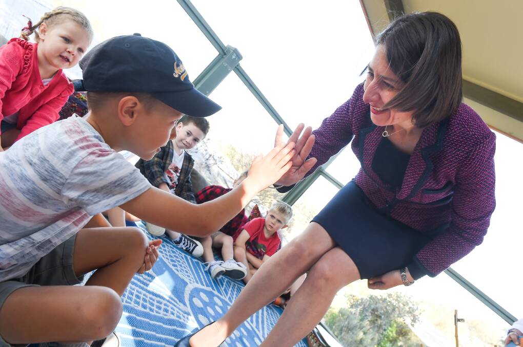 Lending a hand: Premier Gladys Berejiklian gives a high five to Louis Ritchie, 7, on Thursday before her story reading. Picture: MARK JESSER