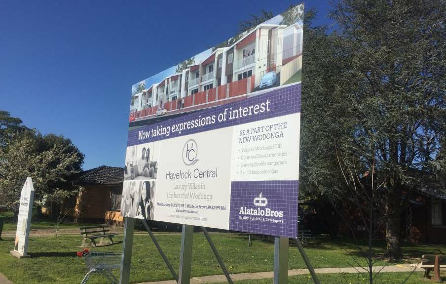 Post: A billboard shows the housing planned for the block that now houses a Lutheran church, manse and op shop.