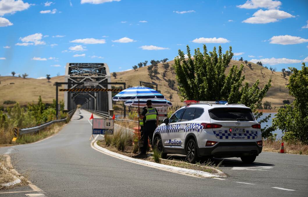 Thin blue line: Two police officers man a border checkpoint at the Victorian end of the Bethanga bridge on Wednesday afternoon. Picture: JAMES WILTSHIRE