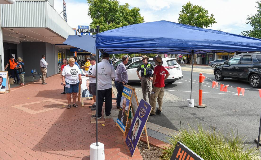 Pay up: A Wodonga Council parking inspector speaks to Labor candidate Mark Tait and campaigner Chip Eling about their shade tent. Picture: MARK JESSER