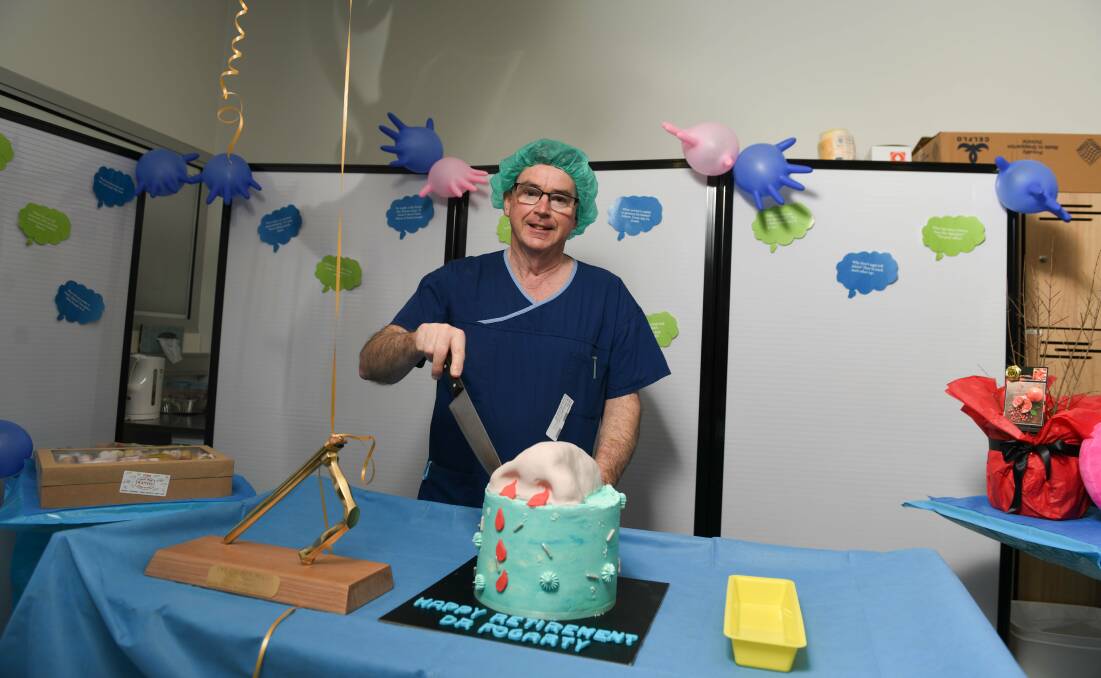 Surgeon Gerard Fogarty starts to cut into his retirement cake which featured a decorative nose atop it. Picture by Tara Trewhella