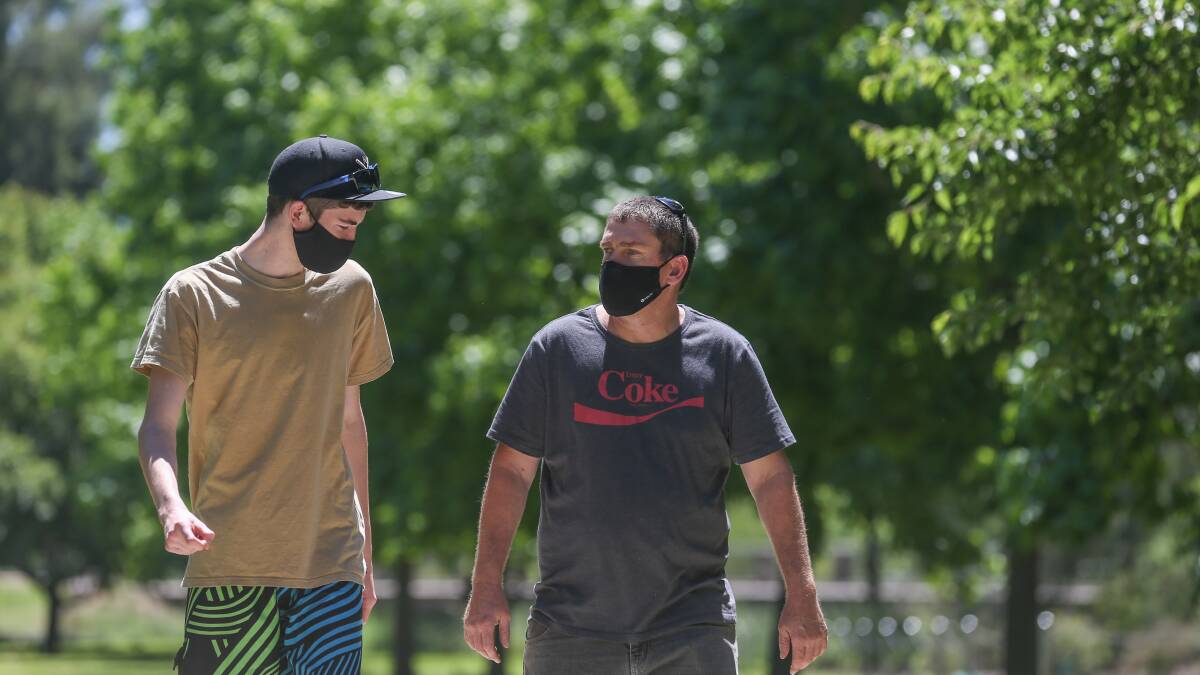 Covered up: Logan Shumack-Bell, 17, and his father Ben Bell walk through Wodonga's Les Stone Park on Sunday morning. Picture: TARA TREWHELLA