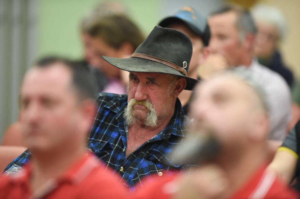 Grim outlook: Former Murray Goulburn employee Jack Britton watches on at Monday night's public meeting with union officials Neil Smith and Andrew Cameron blurred in the foreground. Picture: MARK JESSER
