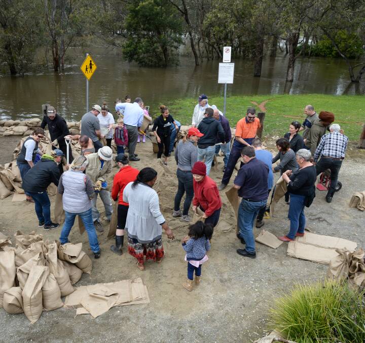 Rallying around: Volunteers pack sandbags to secure Gateway Island businesses from rising water. More than 1000 were formed and added to barriers installed on Sunday night.