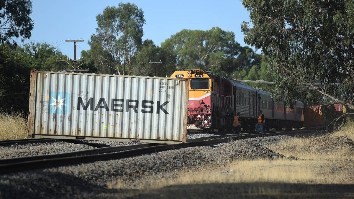 Trapped: A fallen container blocks the V/Line passenger train which was struck by the northbound freight train while travelling through Barnawartha late yesterday afternoon. The goods train is resting against a carriage in the background. Picture: MARK JESSER