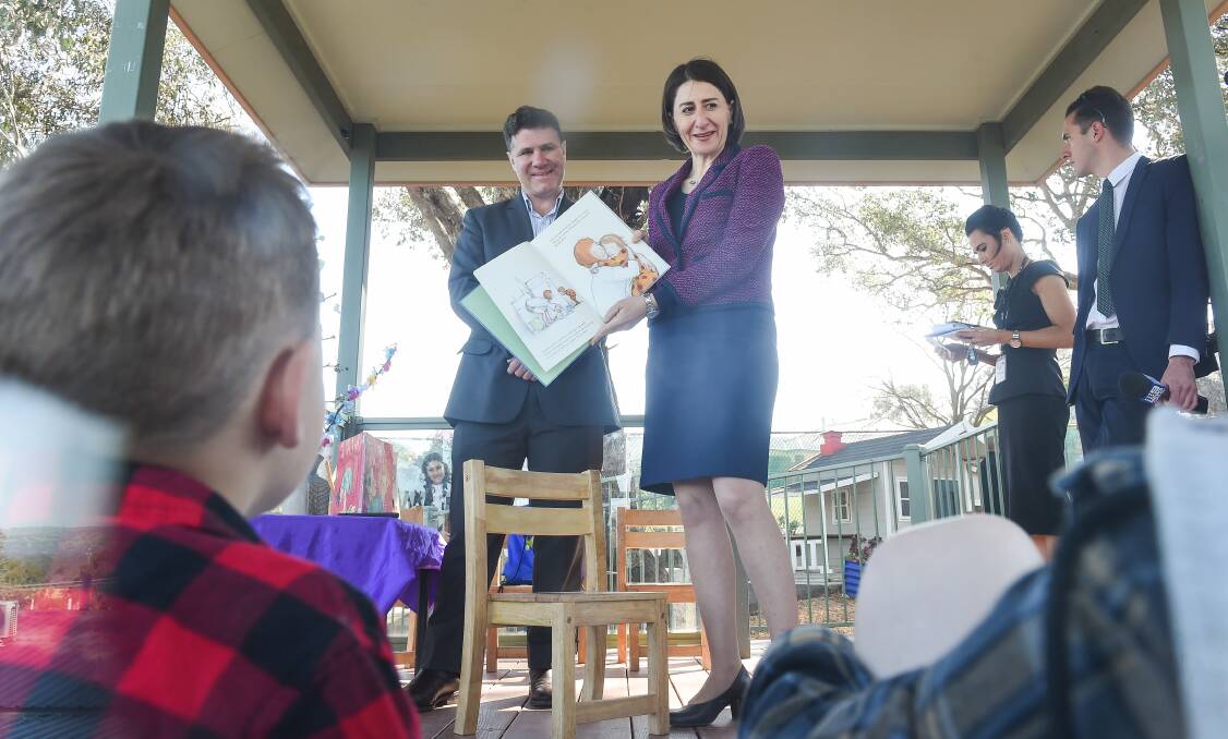 Storyteller: Premier Gladys Berejiklian reads a page to children at West Albury Preschool as member for Albury Justin Clancy watches on. Picture: MARK JESSER