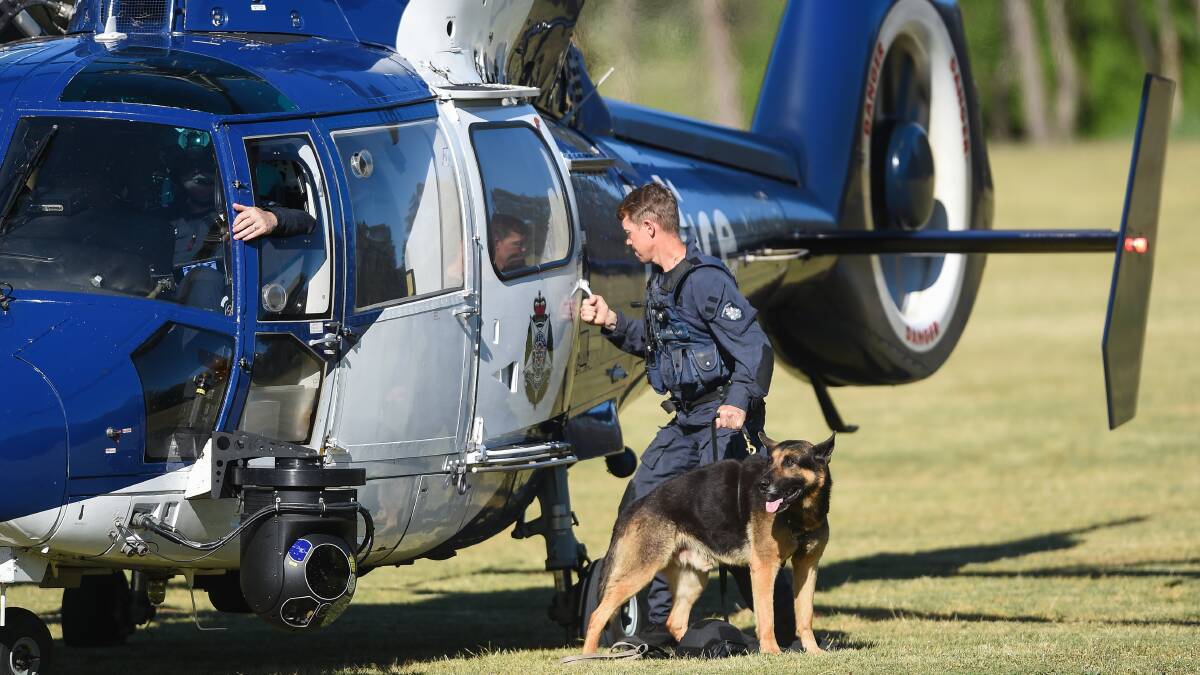 Here to help: A dog handler exits the police helicopter. Both were used in an attempt to find the wanted man. Picture: MARK JESSER