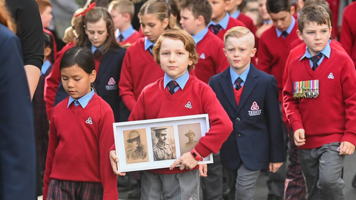 Heir to history: Trinity Anglican College year 2 student Lachlan Morton, 8, carried family portraits of his great-great grandfather and great-great uncles as he marched with fellow students. Picture: MARK JESSER