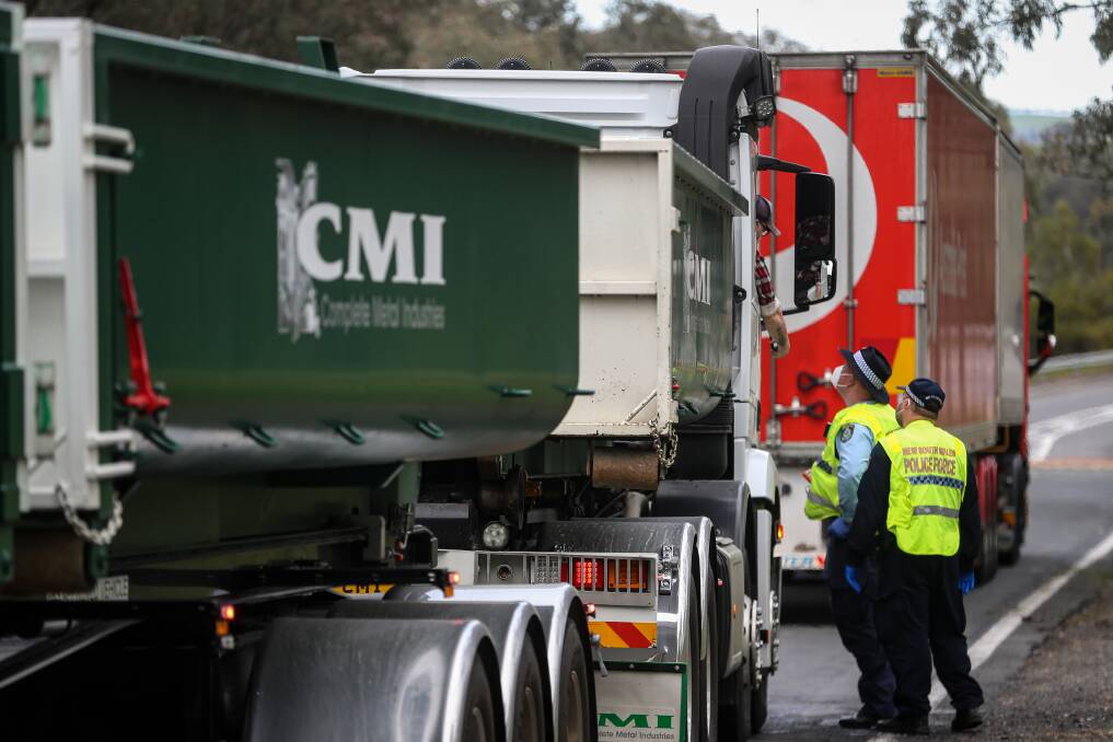 Good job: Police check the details of a truck driver heading south along the Hume Highway at Woomargama this week. The compliance of the freight haulers to new permits has been lauded. Picture: JAMES WILTSHIRE