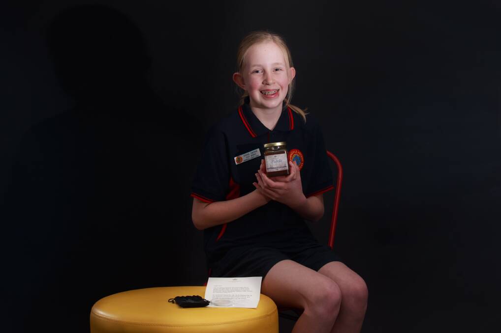 Queen bee: Izzy Berry, 12, with the jar of honey and letter sent to her by NSW Governor David Hurley after his visit to her school earlier this year. Picture: SIMON BAYLISS
