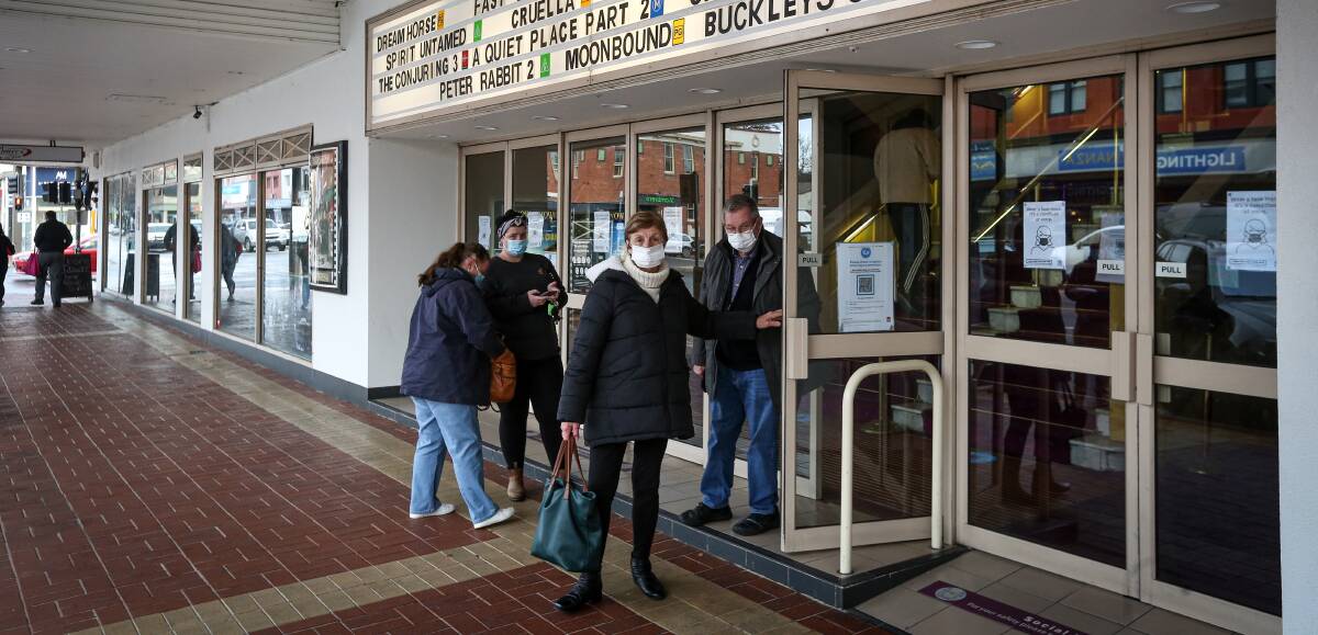 Covered up: Geanette Jacobs holds the door for husband Graeme on Sunday. They were among scores who attended the movies in masks. Picture: JAMES WILTSHIRE