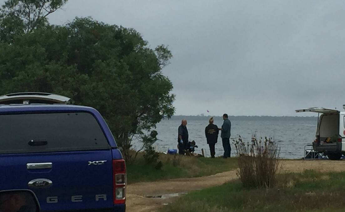Grim scene: Police investigators on the shore of Lake Victoria in Gippsland where a Springhurst man was fatally injured by a fire cracker on New Year's Eve.