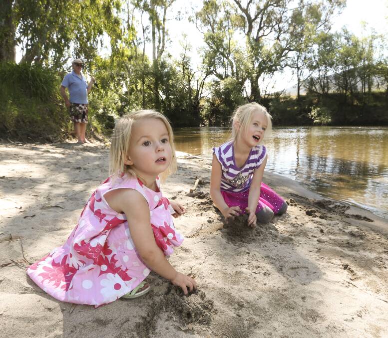 Fun in the sun: The Bartel sisters Holly, 2, and Ella, 5, play alongside the Kiewa River at Kergunyah Reserve on Monday afternoon. They were visiting their grandparents after travelling from Melbourne. Picture: ELENOR TEDENBORG