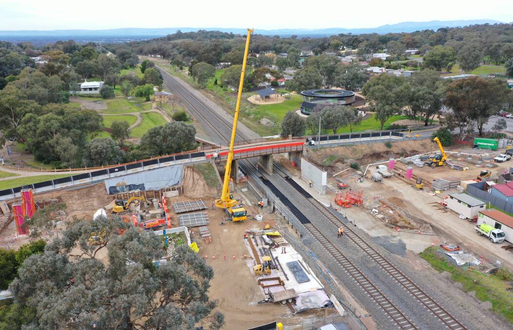 A crane is used to help with pillar work for the new bridge being built across the railway lines at Glenrowan. The fresh visitors' centre can be seen in the background. Picture from the ARTC.