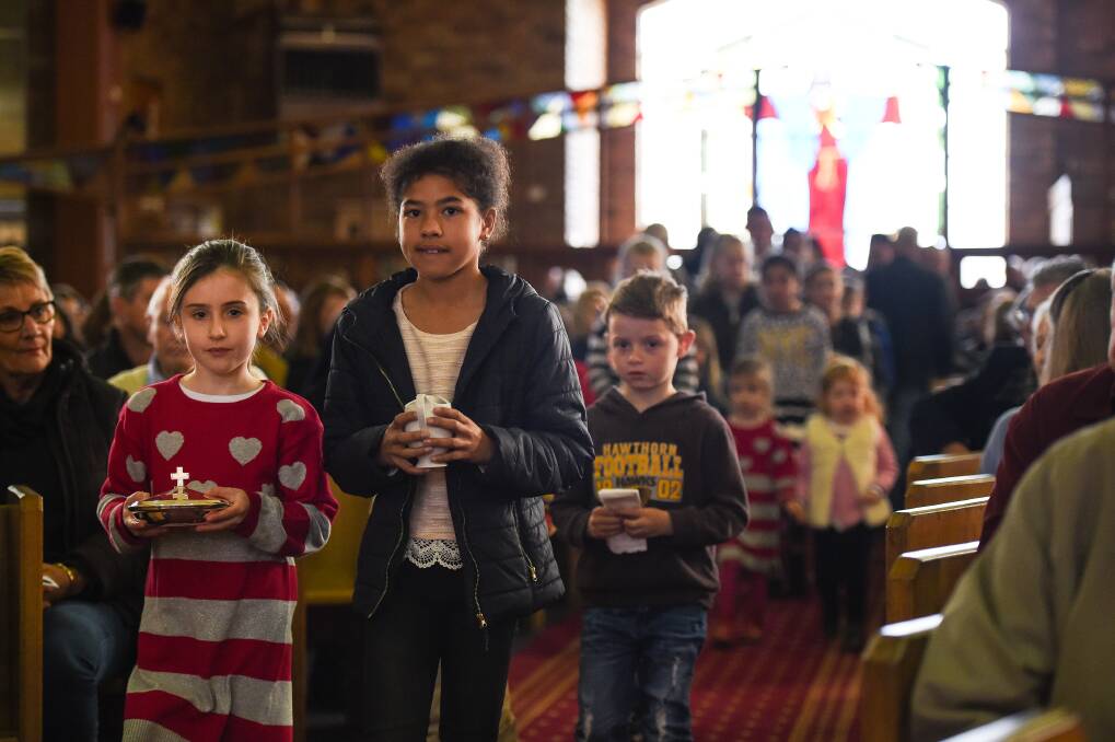 Memorable day: Children with gifts as part of the offertory at Father Flanagan's final service. Pictures: MARK JESSER