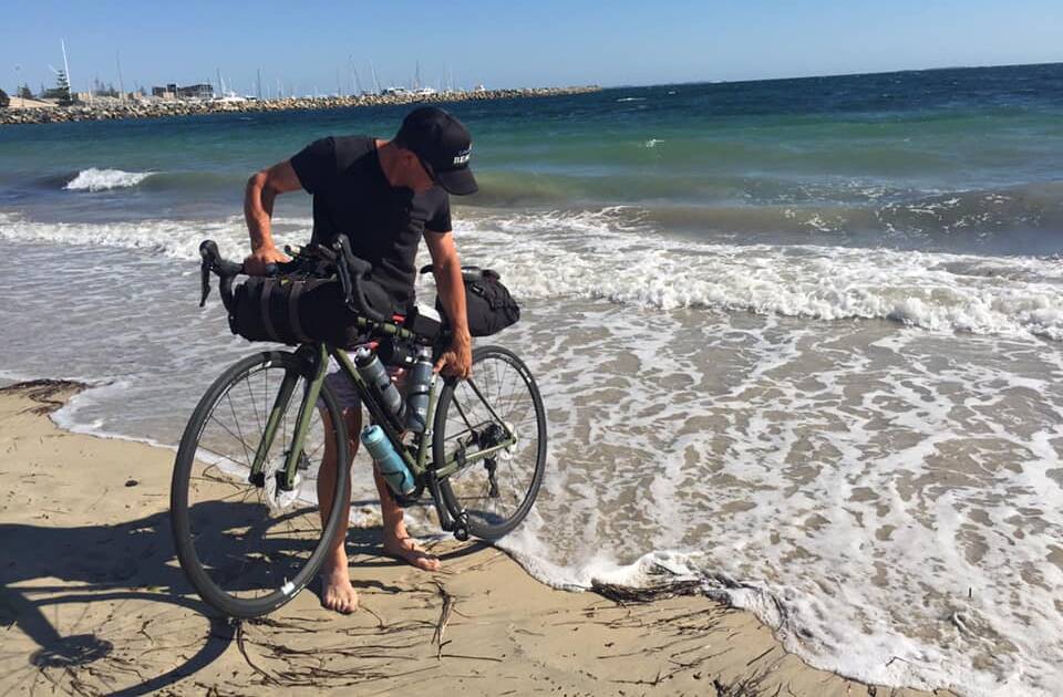 Starting point: Marty Cross dips his bike's rear wheel in the Indian Ocean at Fremantle at the outset of his cross country ride in March.