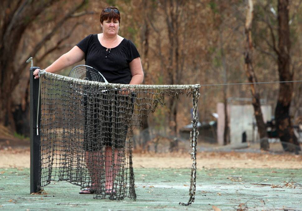 Lead plaintiff: Sharon Weber, pictured in 2010, with the remains of a burnt net at Gerogery Tennis Club which was hit by the bushfire that started at Walla tip.