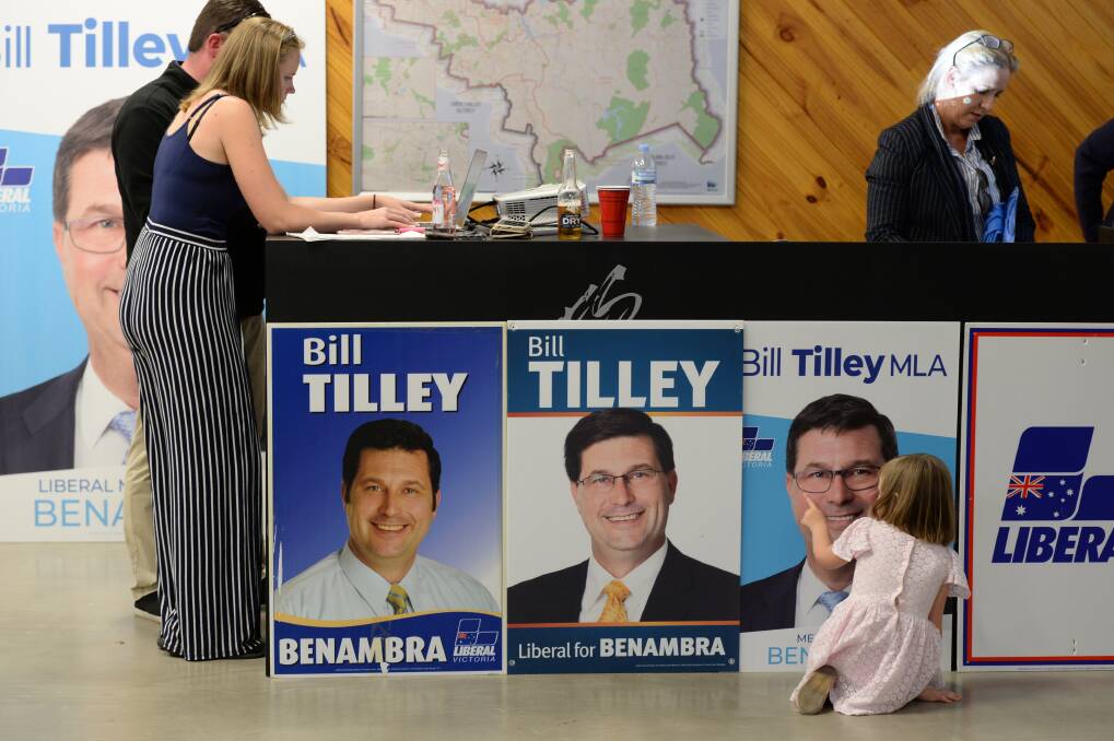 Generational change: A youngster traces around Bill Tilley's face on his 2018 election poster which stood alongside previous campaign placards at his election party on Saturday night. Picture: MARK JESSER