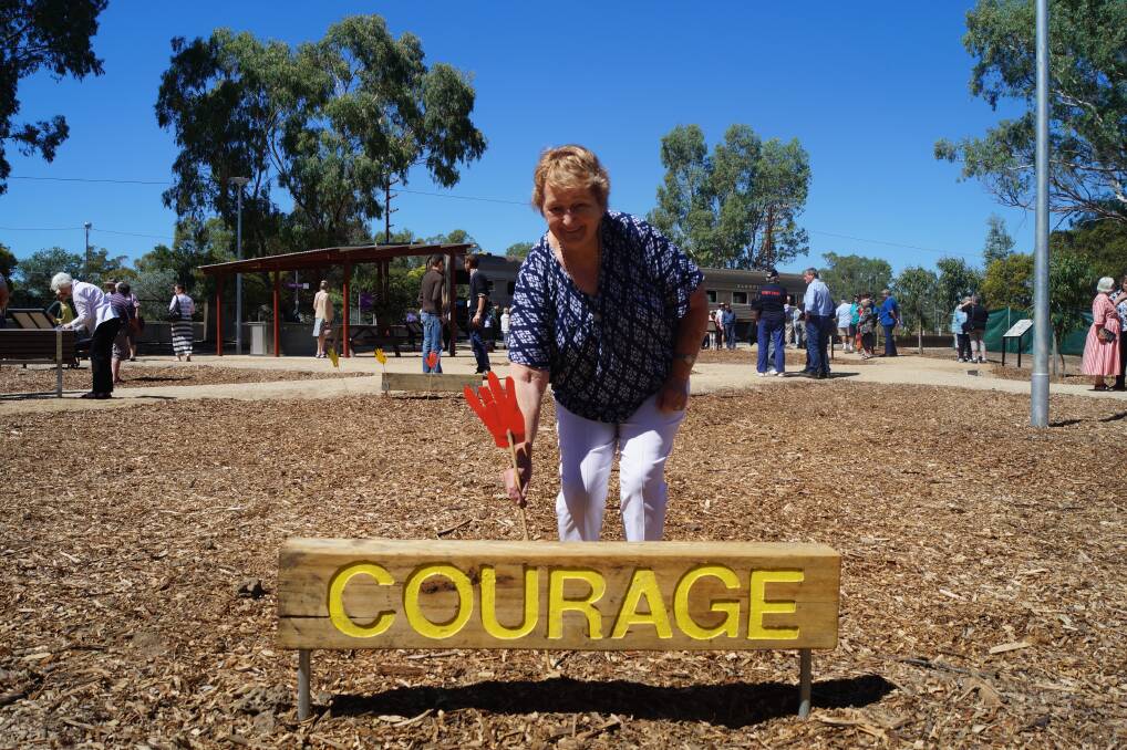 Touching moment: Gwen Ziebell in the memorial garden after its opening on Sunday. She chose to be photographed with the sleeper featuring the word 'Courage' because it best reflected her view of the response shown towards the tragedy by Violet Town. Picture: STRATHBOGIE COUNCIL