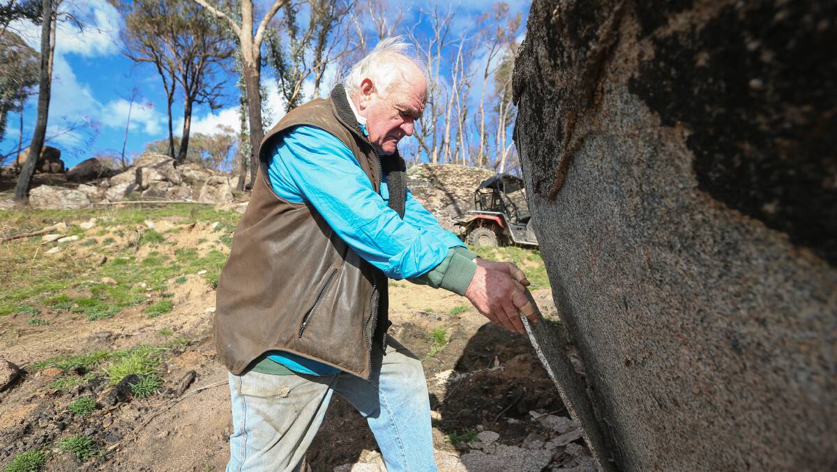 Like plasterboard: David Lyons demonstrates how easily pieces of burnt rock can be peeled away after they have been scarred by fire. Picture: JAMES WILTSHIRE