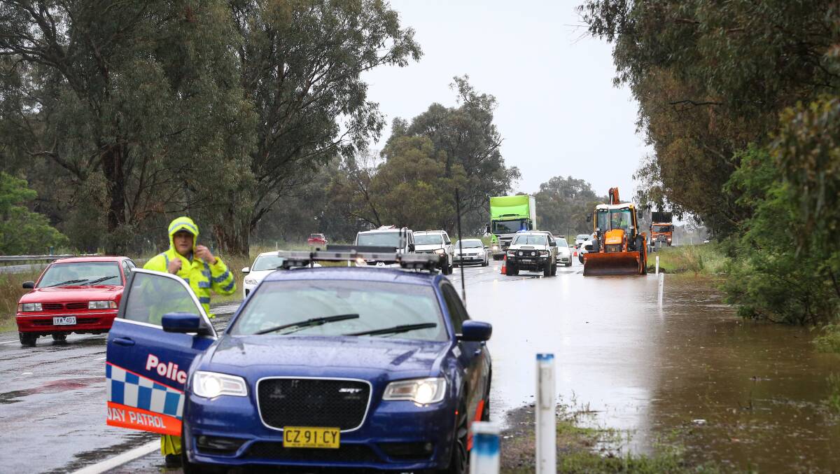 Damp duty: A policeman prepares to assist colleagues in directing traffic around water flowing over the Hume Freeway.