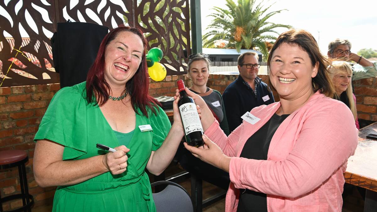 All yours: Indi election candidate Liz Fisher signs a bottle of Bobbie Burns shiraz for her cousin Danielle Roberts who successfully bid for it. Picture: MARK JESSER