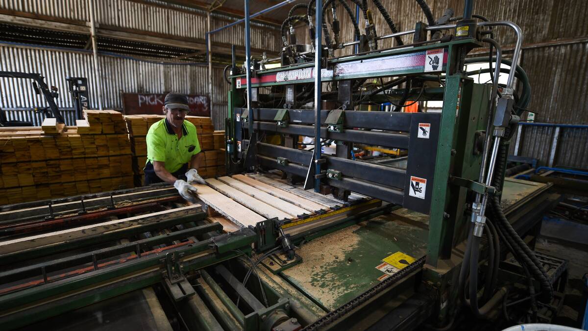 On the production line: Stephen Williams feeds short planks into the machine which then nails pallets together. They are then pushed through to a painting unit which colours their sides in the blue used by the CHEP company. Picture: MARK JESSER