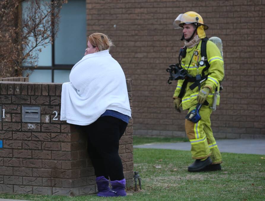 Left feeling shaken: A woman who occupied the front of two units in a block that was hit by a suspicious fire on Tuesday afternoon. Paramedics gave her a towel after she was treated for breathing difficulties.