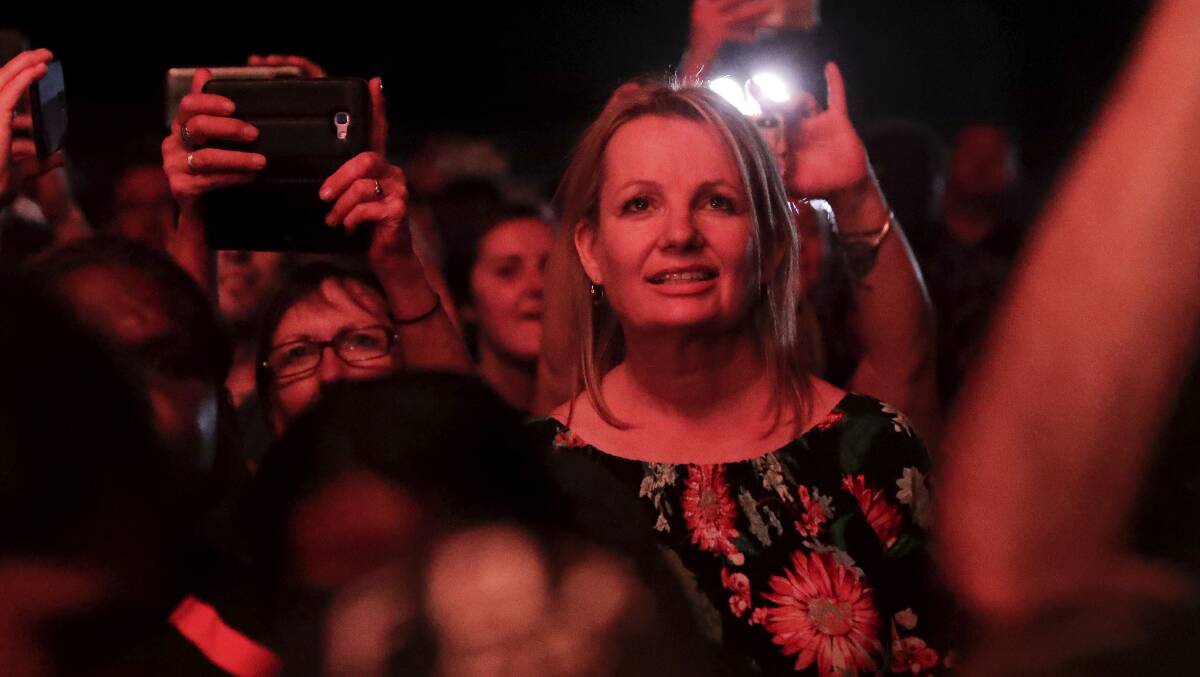 Face in the crowd: Environment Minister Sussan Ley watches a predecessor, Peter Garrett, in his role as Midnight Oil singer, entertain the crowd at a celebration on Sunday night to mark the end of climbing of Uluru. 