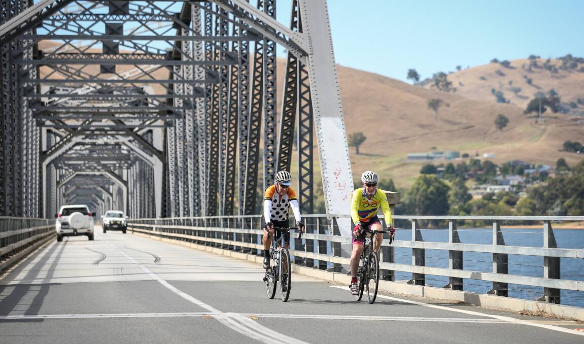 Cyclists cross the Bethanga Bridge into NSW with Bellbridge in the background. A master plan has proposed having a dedicated bridge across Lake Hume for riders, runners and walkers. Picture by James Wiltshire