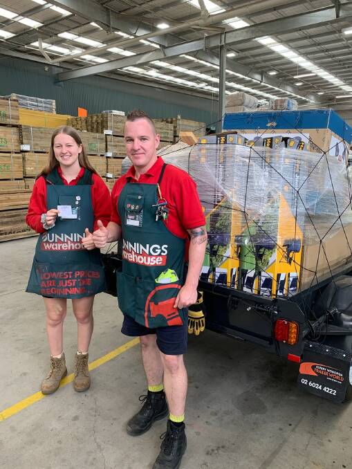 Draw done: Wodonga Bunnings cashier Emily Orzeszko and operations manager Jamie Wolf, also a Kokoda 2020 participant, with the winning ticket and trailer load of prizes that were given away in one package.